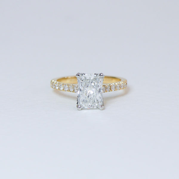 Radiant cut diamond fleur ring with diamond set band.