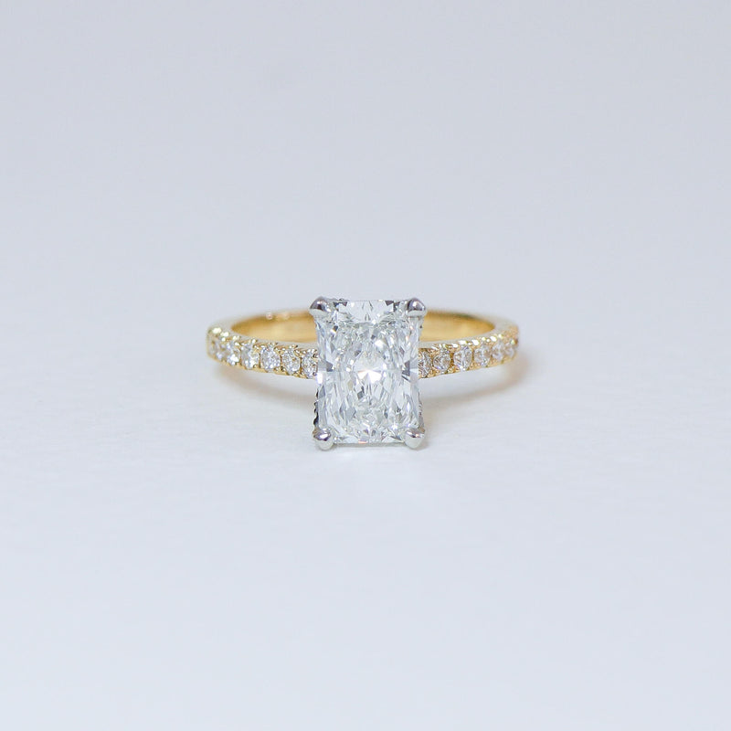 Radiant cut diamond fleur ring with diamond set band.